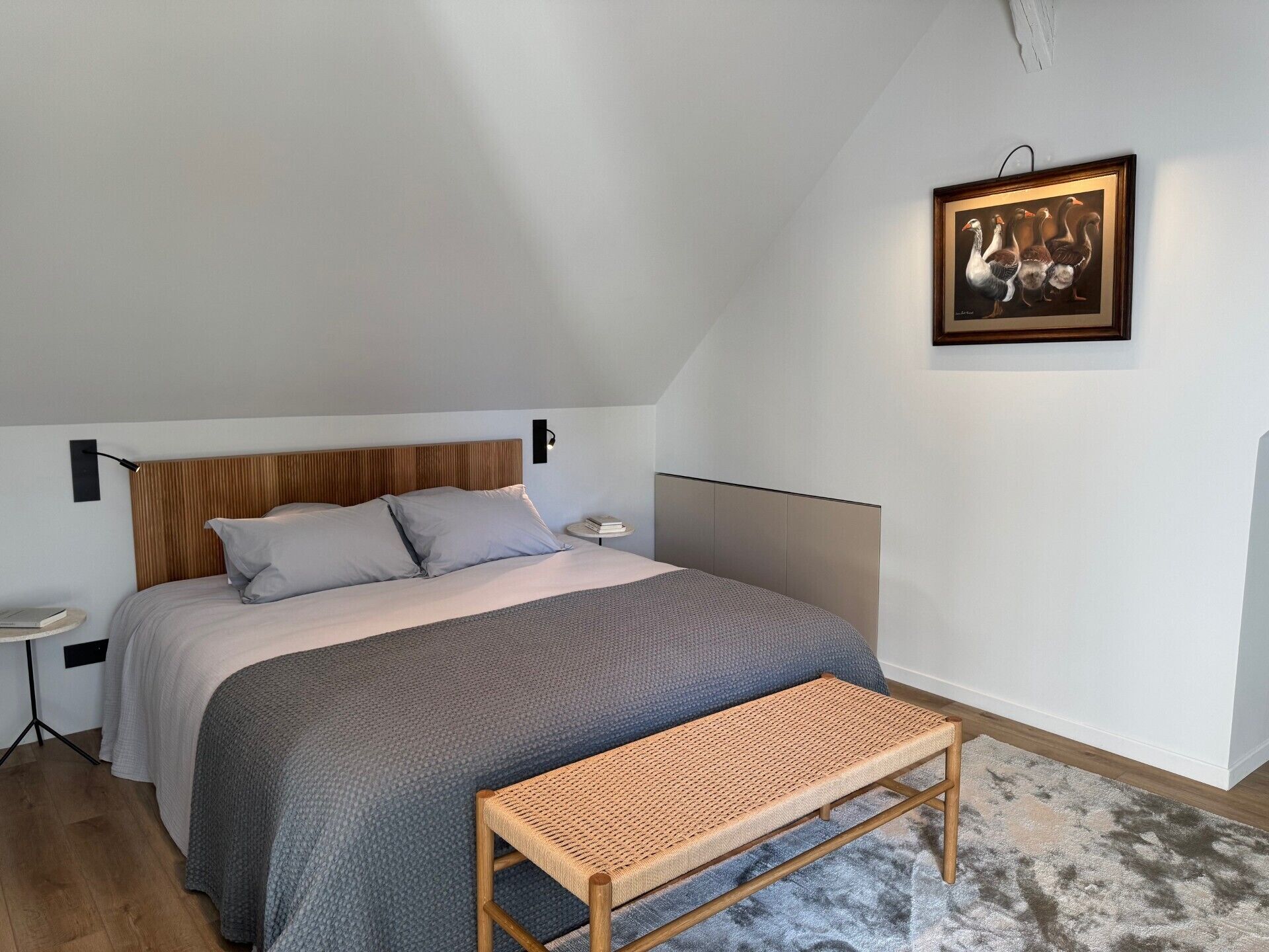 Une chambre à coucher avec un lit, une table de chevet, une lampe et un tableau au mur.