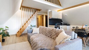 Un espace de vie de style loft avec un escalier en bois, un canapé, un coin repas et une cuisine.