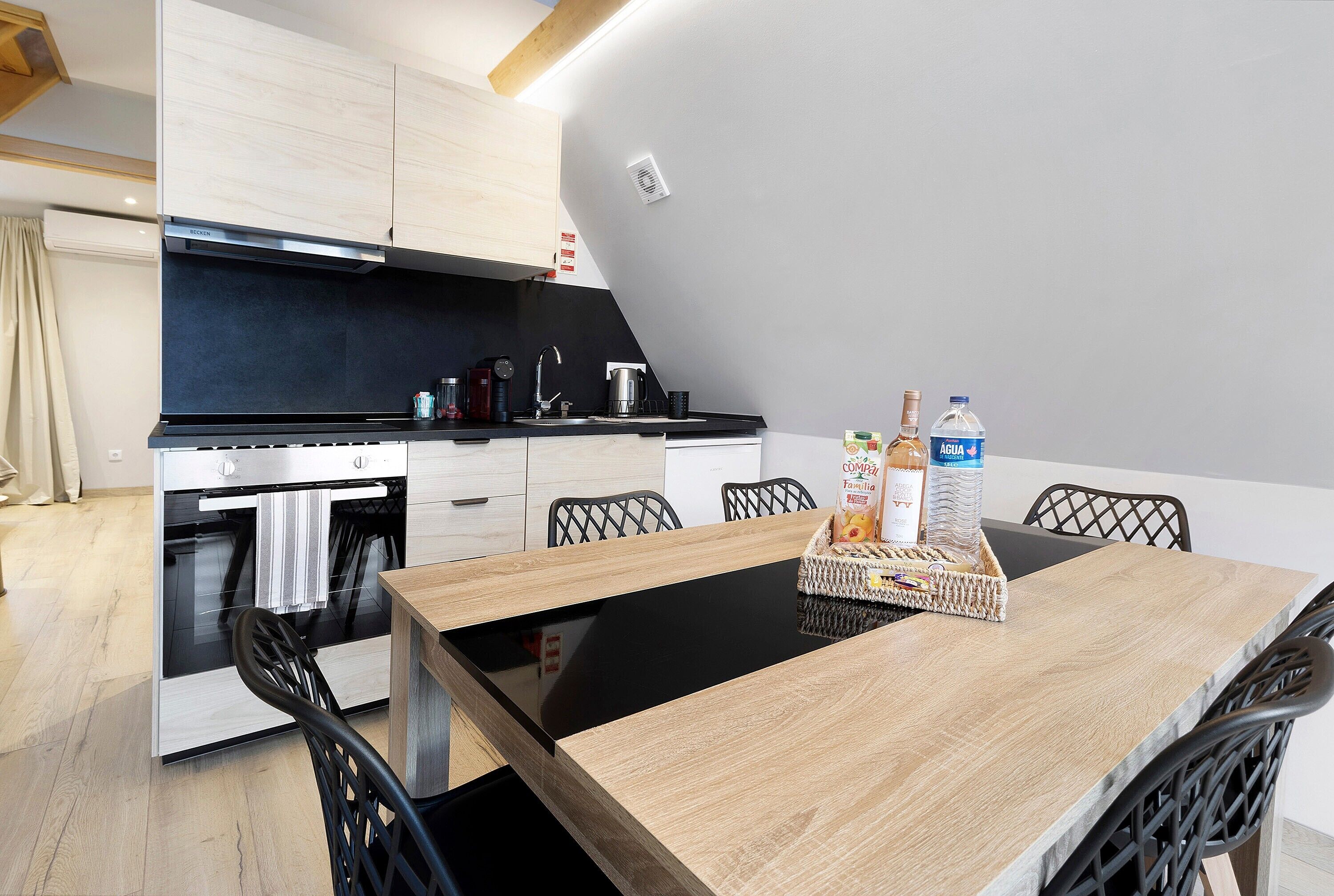 A modern kitchen with a built-in oven, a dining table with chairs, and a kitchen island with a sink.