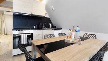 A modern kitchen with a built-in oven, a dining table with chairs, and a kitchen island with a sink.
