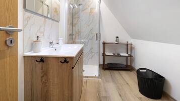 Un baño moderno con tocador de madera, cabina de ducha de vidrio y estante de madera.