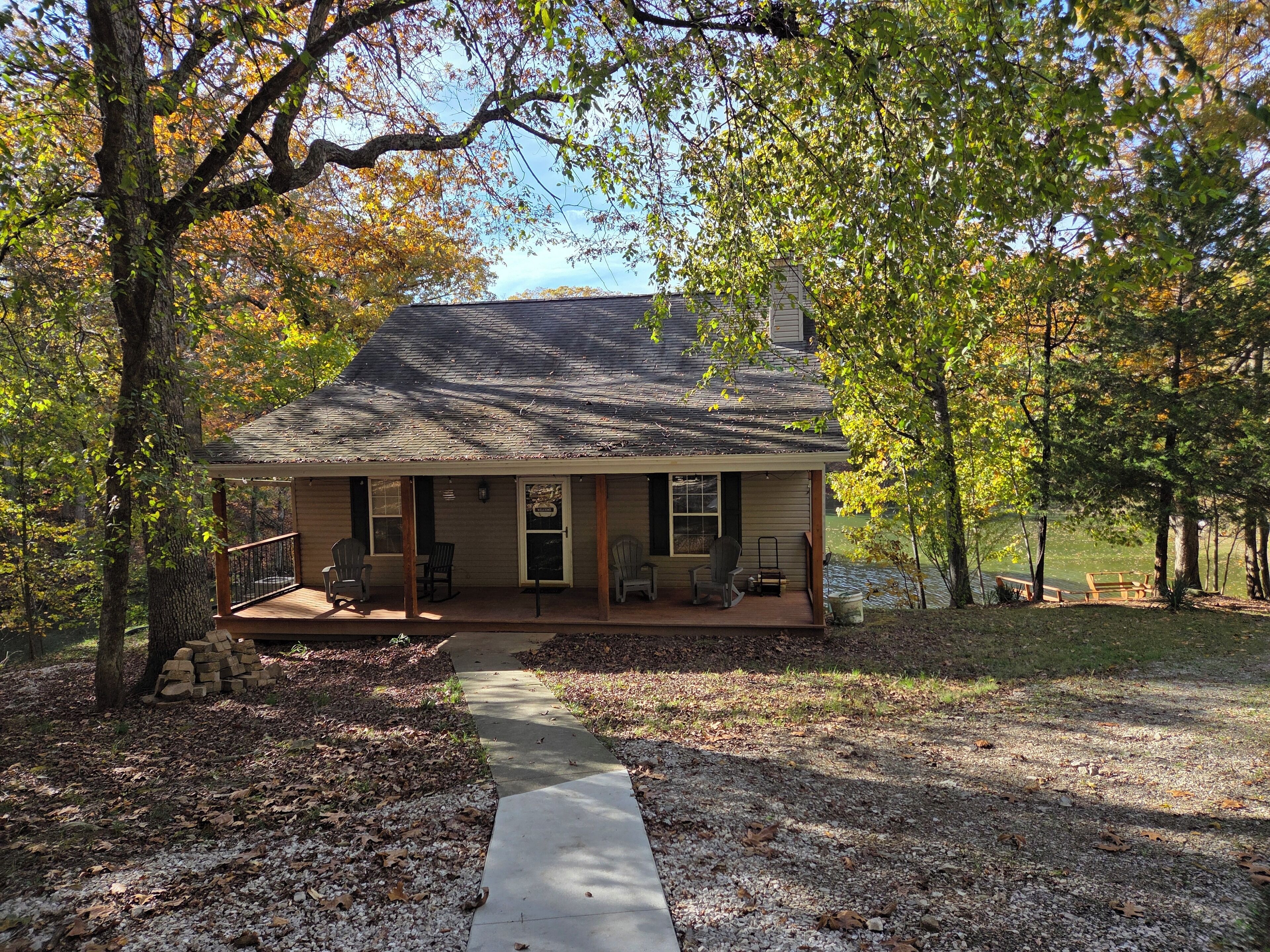 A cabin with a porch, two chairs, and a pathway leading to the entrance.