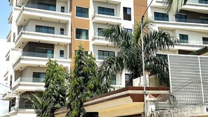 Un edificio residencial de varios pisos con balcones y una entrada protegida por una reja.