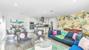 A modern living room with a grey sofa, a round coffee table, and a dining area with a glass table and chairs. - Pool, Hot Tub & Putting Green Near Deerfield Beach Oasis on Fourth by Avantstay (Deerfield Beach)