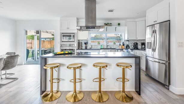 A modern kitchen with a central island, stainless steel appliances, and a view to the backyard. - Pool, Hot Tub & Putting Green Near Deerfield Beach Oasis on Fourth by Avantstay (Deerfield Beach)