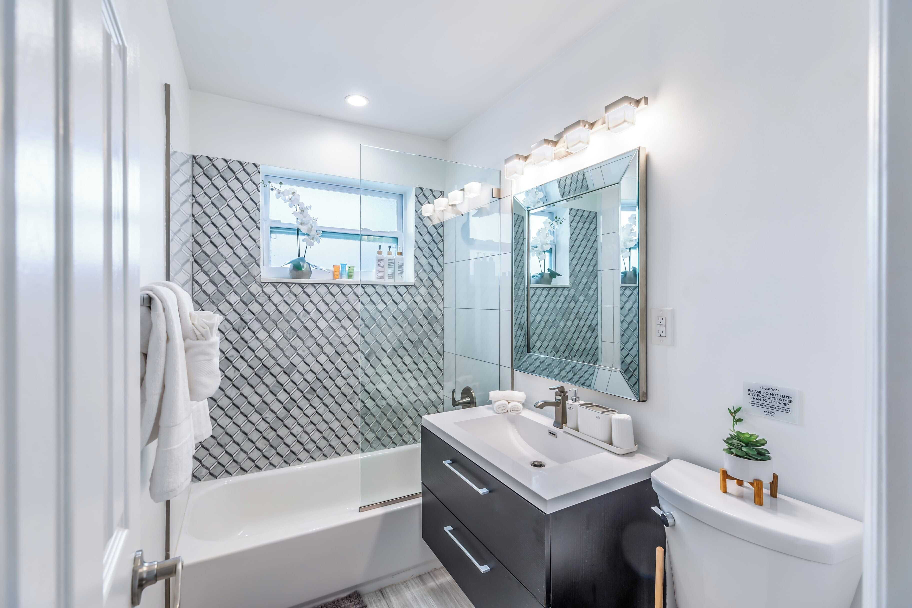 A modern bathroom with a glass-enclosed shower, a vanity with a sink, and a toilet.