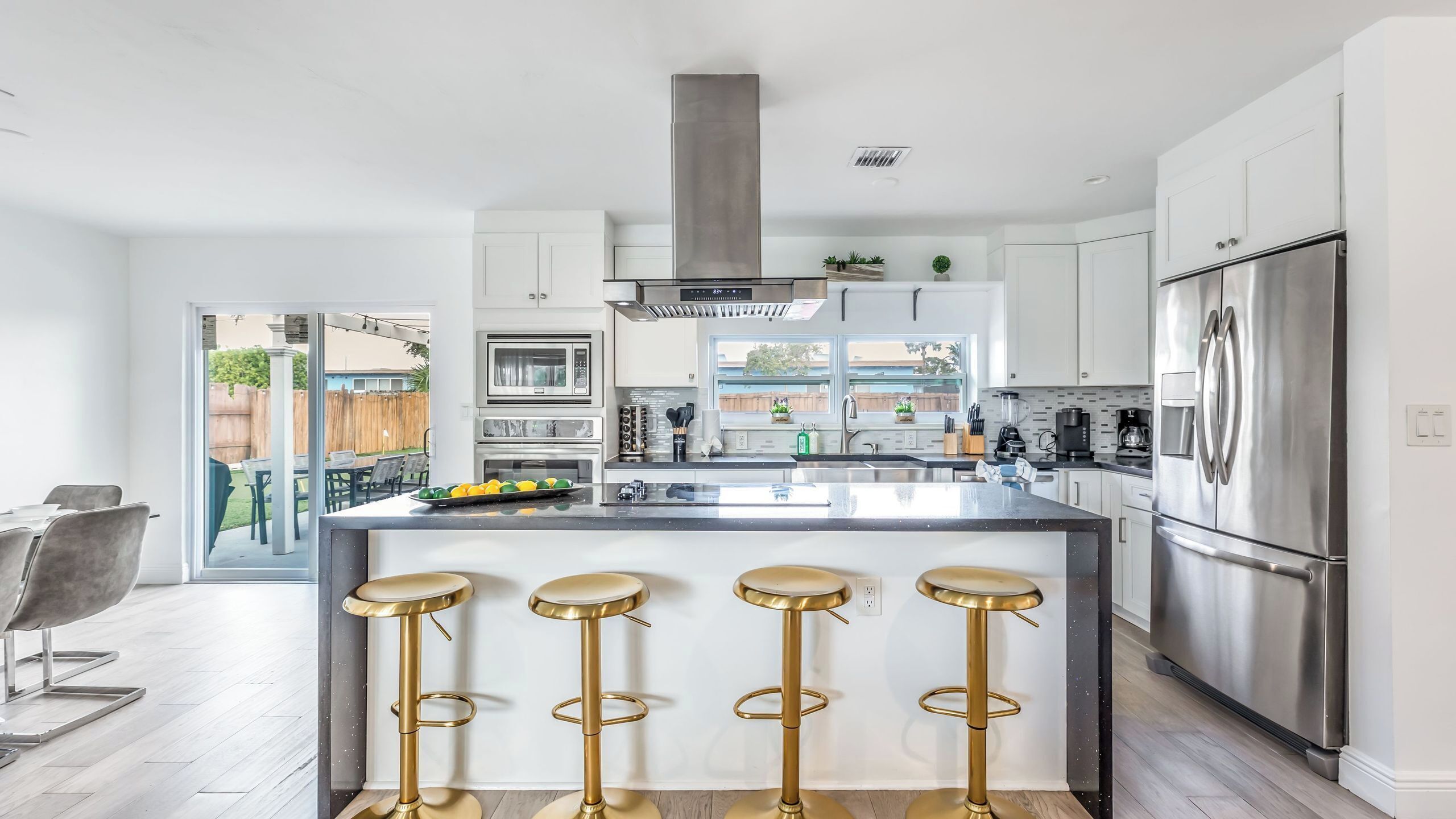 Una cocina moderna con una isla central, electrodomésticos de acero inoxidable y una zona de asientos con taburetes de bar.