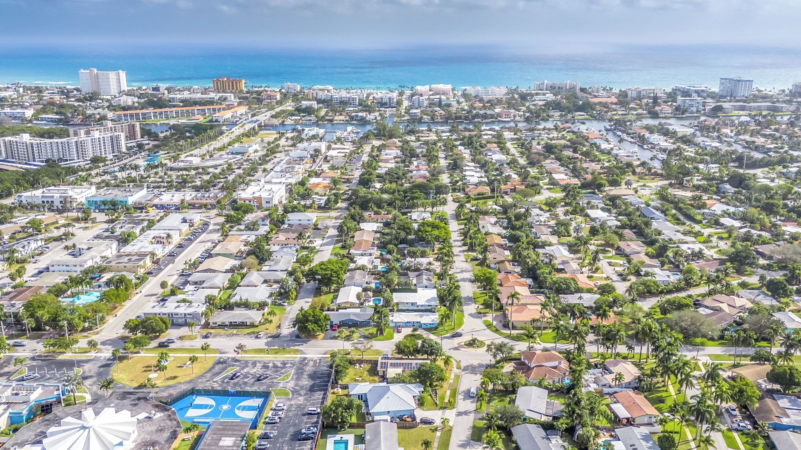 Vue aérienne d’un quartier résidentiel avec des maisons, des rues et une grande étendue d’eau en arrière-plan.