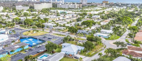 A residential area with multiple houses, a swimming pool, and a large building in the background.