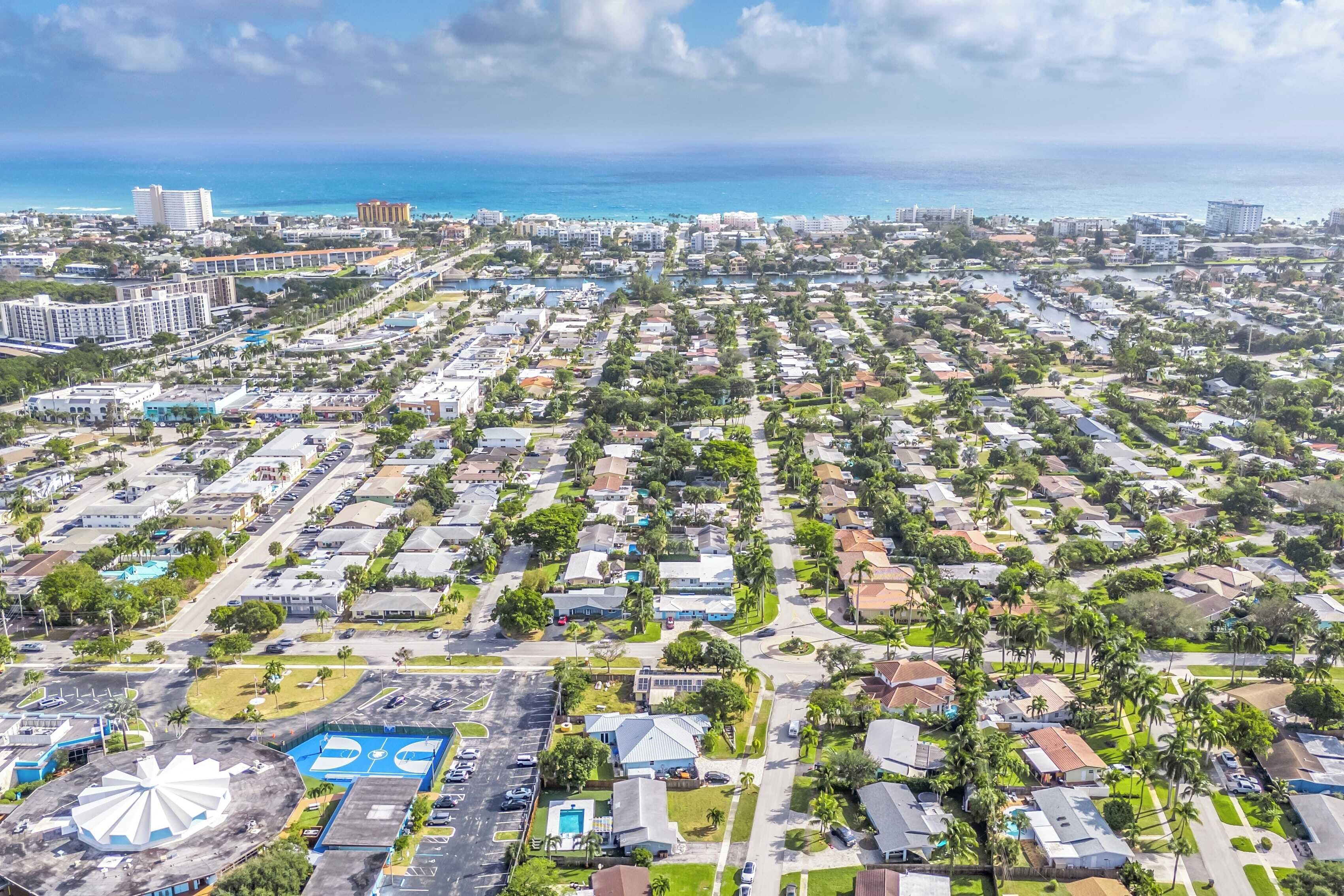 An aerial view of a residential area with houses, roads, and a large body of water in the background.