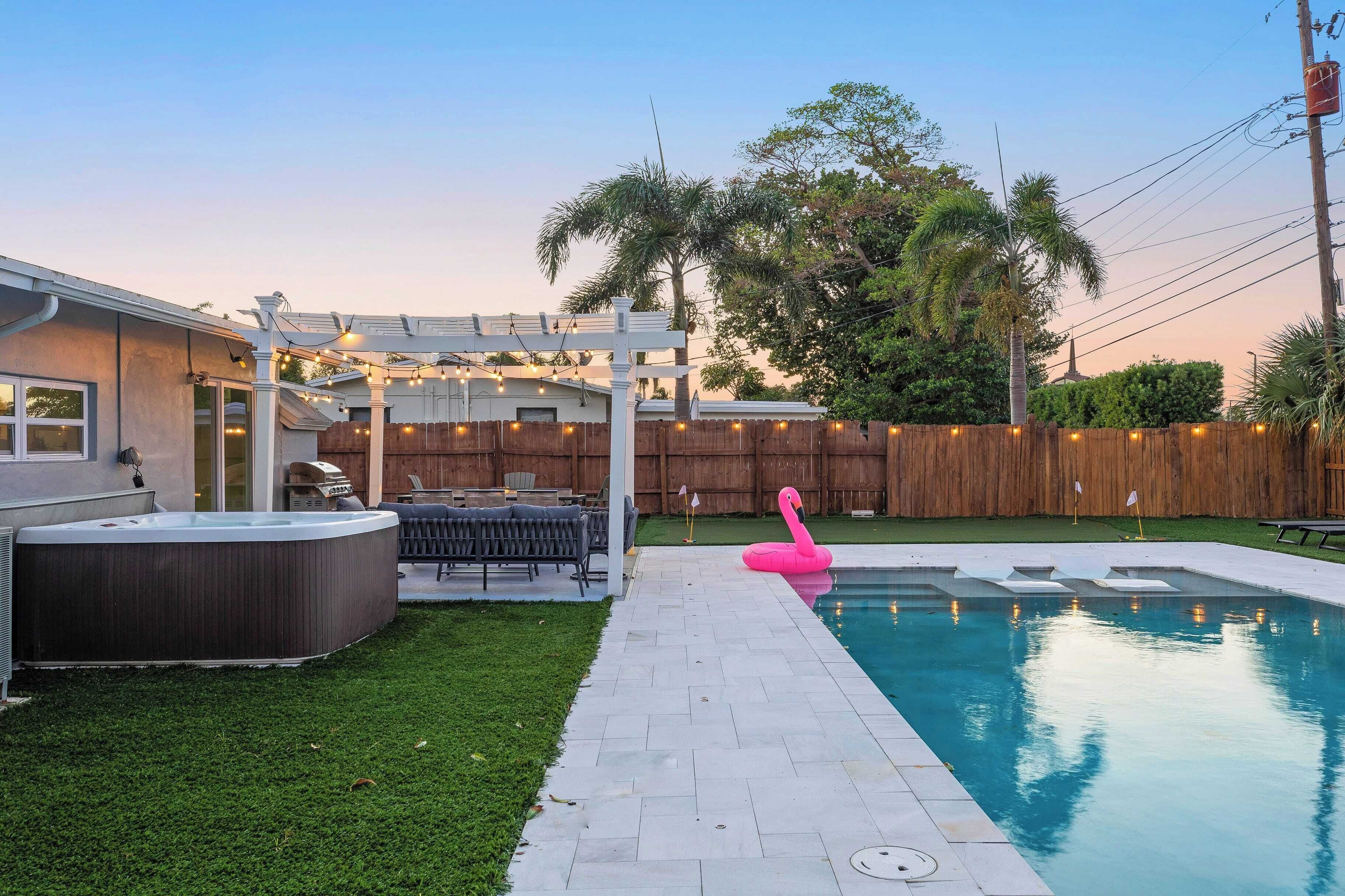Un patio trasero con piscina, jacuzzi y terraza de madera.