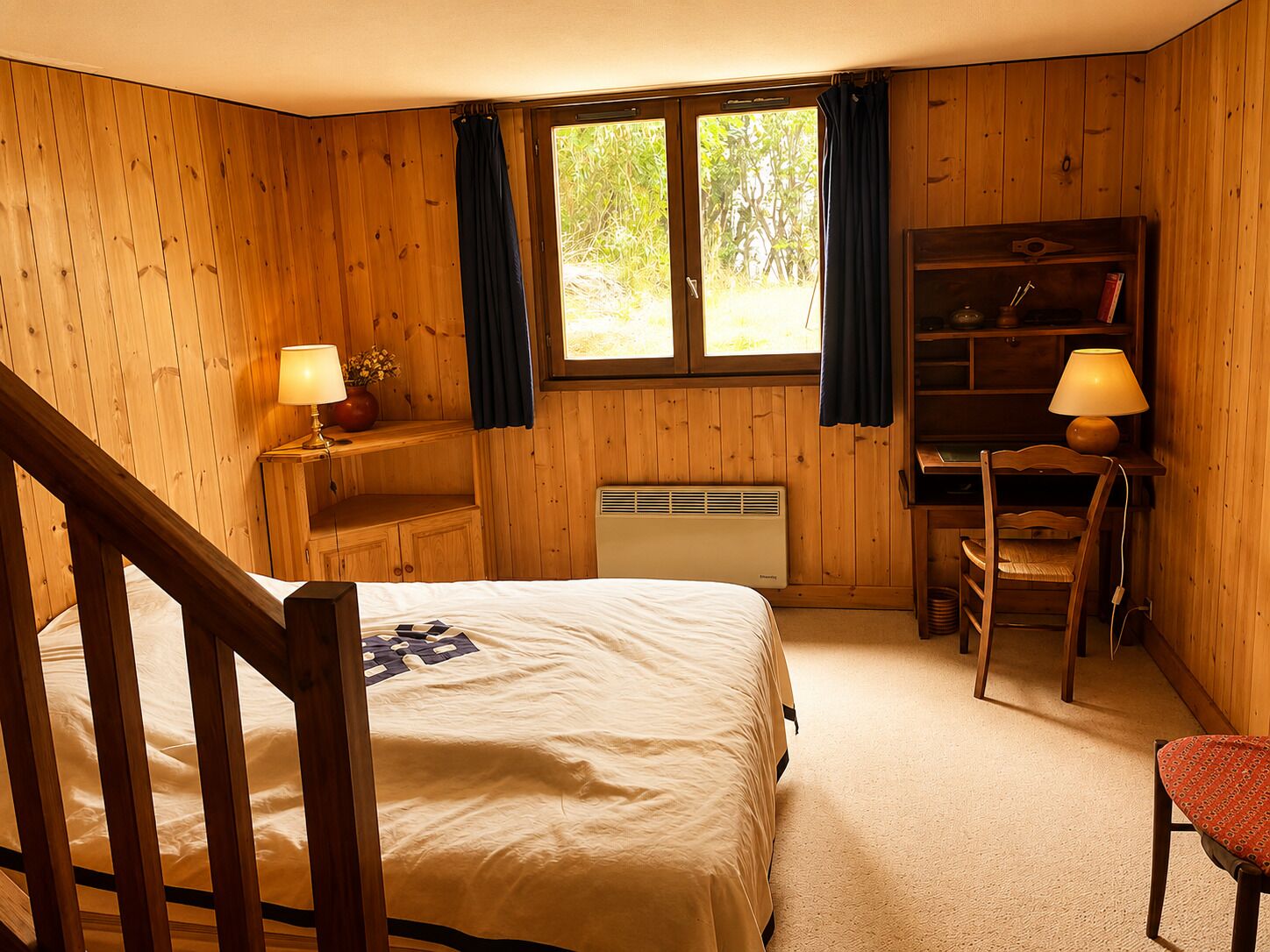 Une pièce en bois comprenant un lit, un bureau, une chaise et une fenêtre avec des rideaux.