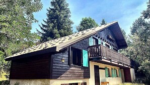 Een houten chalet met een balkon, een raam met luiken en een stenen fundering.
