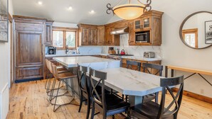 A kitchen with wooden cabinets, a marble countertop, and a large island with bar stools.
