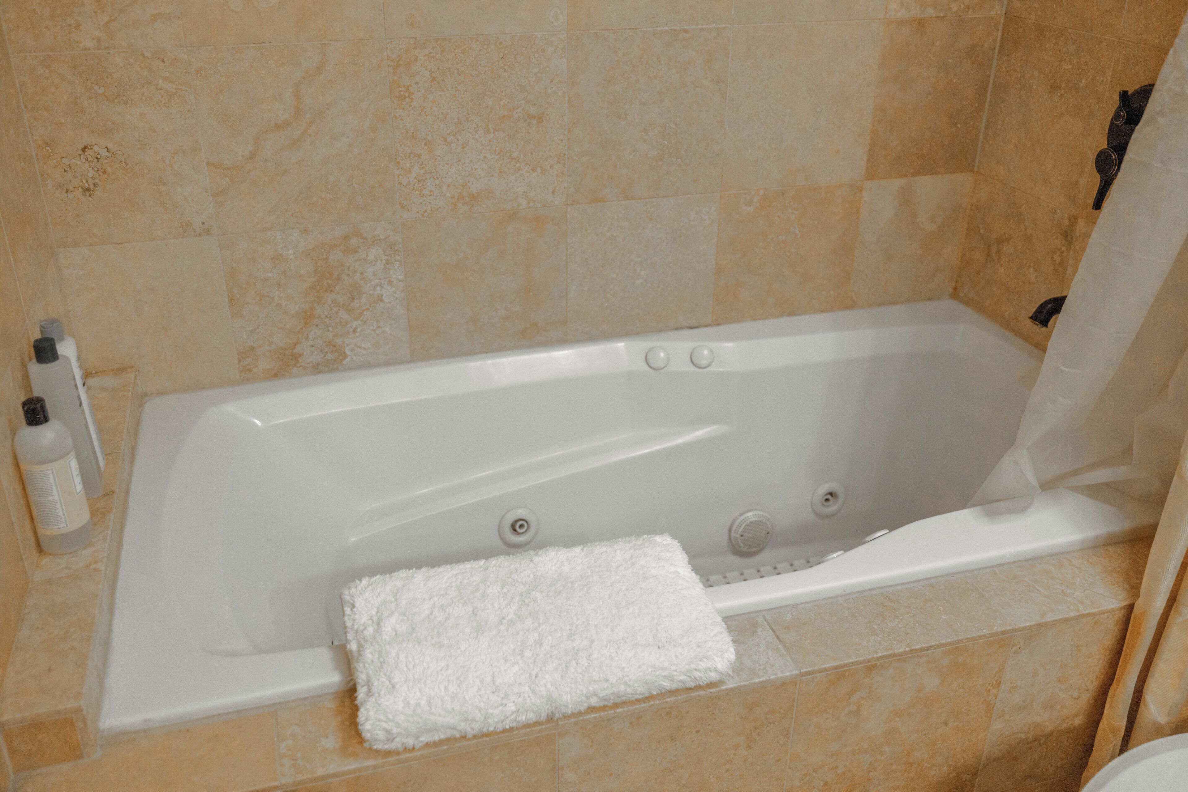 Ein Badezimmer mit einer Badewanne, einem weißen Handtuch und Pflegeprodukten auf der Ablagefläche.