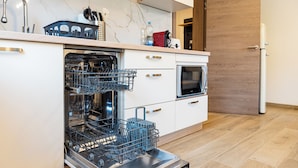 Een keuken met een vaatwasser, oven en een houten deur.