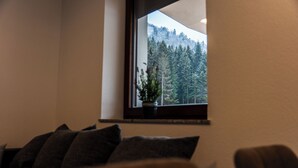 Een kamer met een raam met uitzicht op een bebost gebied.