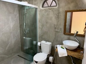A modern bathroom with a glass-enclosed shower, a toilet, a sink, and a mirror.