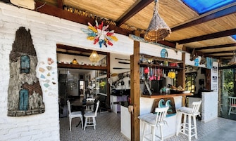 A rustic interior with a white brick wall, a wooden ceiling, and a bar area with stools.