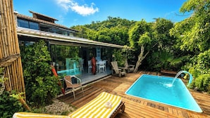 A modern house with a glass-enclosed patio, a swimming pool, and lush greenery. - Pousada Ondas da Grande – Penha/SC (Penha)