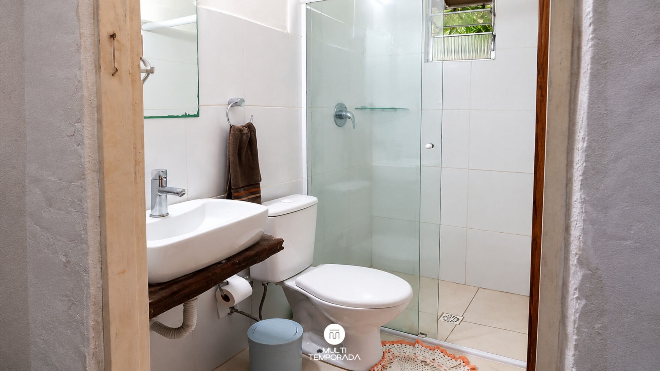 A bathroom with a white sink, toilet, and glass shower enclosure.