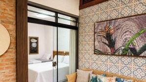 A room with a bed, a sofa, a patterned wall, and a framed picture. - Pousada Ondas da Grande – Penha/SC (Penha)