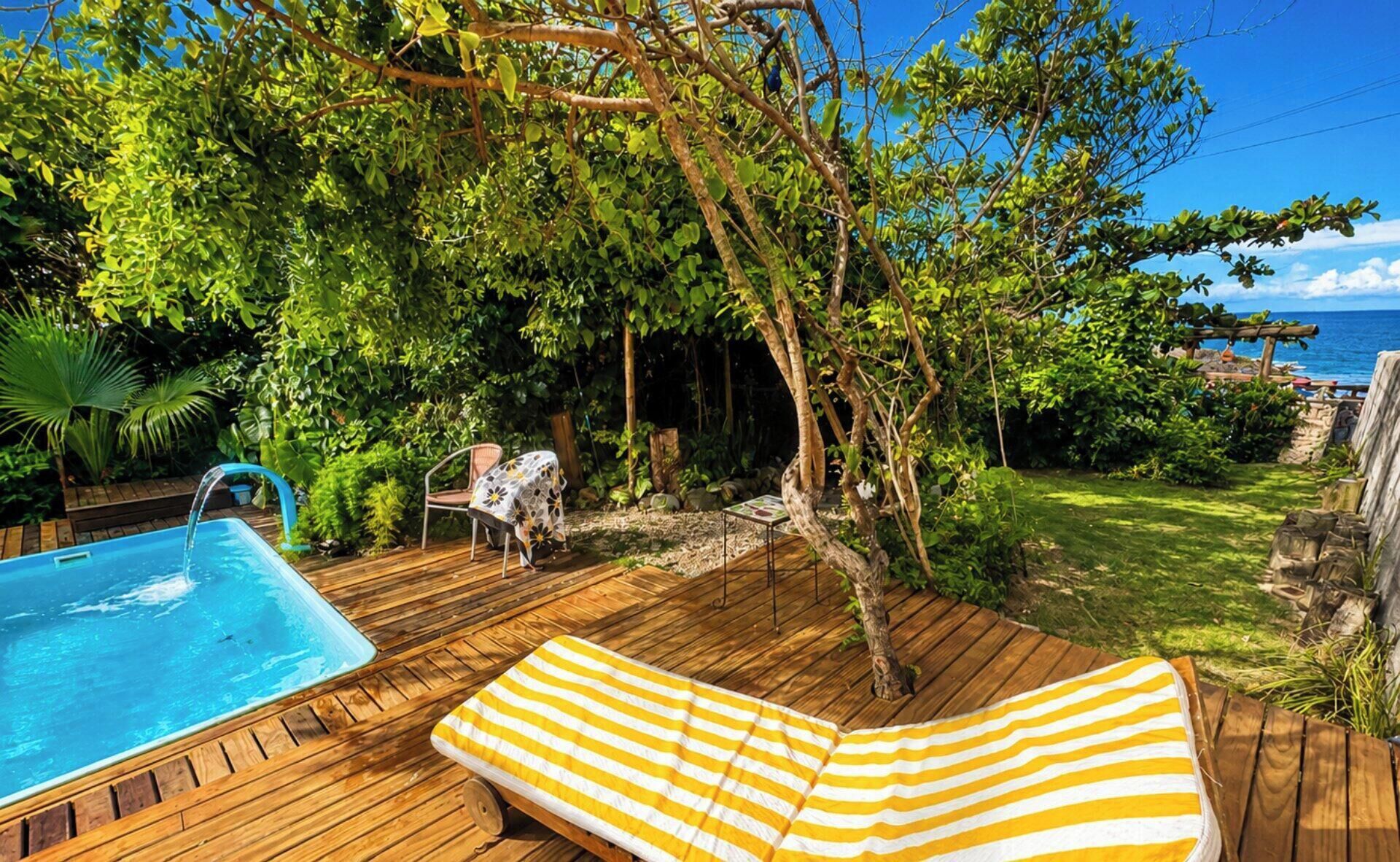 Eine Holzterrasse mit Schwimmbad, Liegestuhl und Tisch mit Tischdecke.