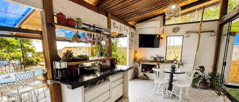 A kitchen with a wooden ceiling, white cabinets, and a dining area with white chairs.