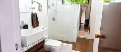 A bathroom with a white sink, toilet, and shower area.