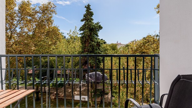 A balcony with a view of trees and a distant building.