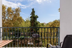 A balcony with a view of trees and a distant building.