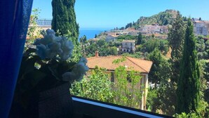 A coastal town with buildings on a hillside, a clear blue sky, and a view of the sea. - Elegant Sicilian villa in the heart of Taormina - 3 bedrooms, 3 bathrooms. (Taormina)