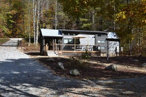 A cabin with a covered porch, a garage, and a gravel driveway.
