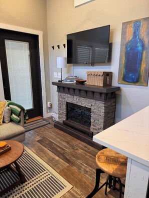 A modern living room with a fireplace, a flat-screen TV, and a dining area.