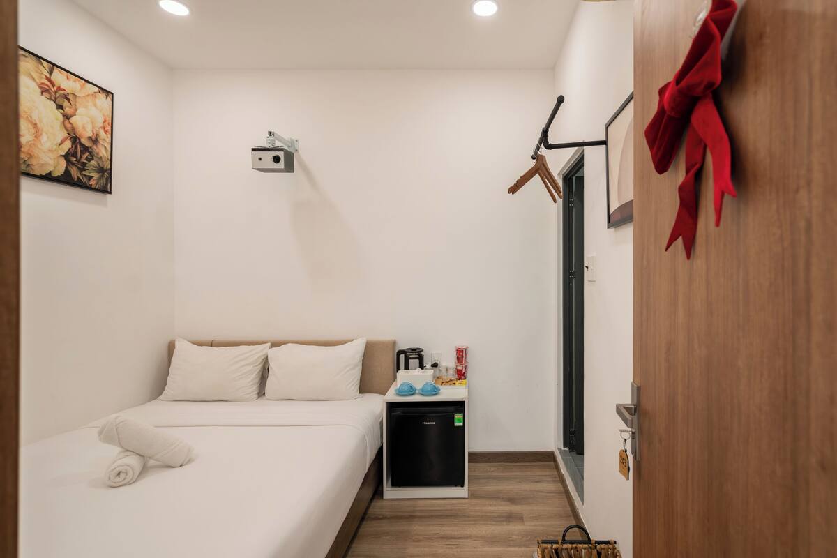 Ein Hotelzimmer mit Bett, einer kleinen Küchenzeile, einer an der Wand montierten Kamera und einer Tür mit roter Schleife.