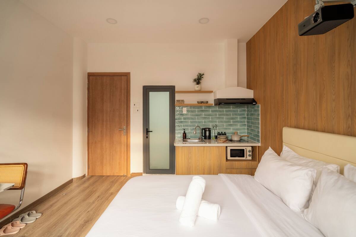Ein Hotelzimmer mit Bett, Holztür, einer Küchenzeile und einer kleinen Sitzecke.