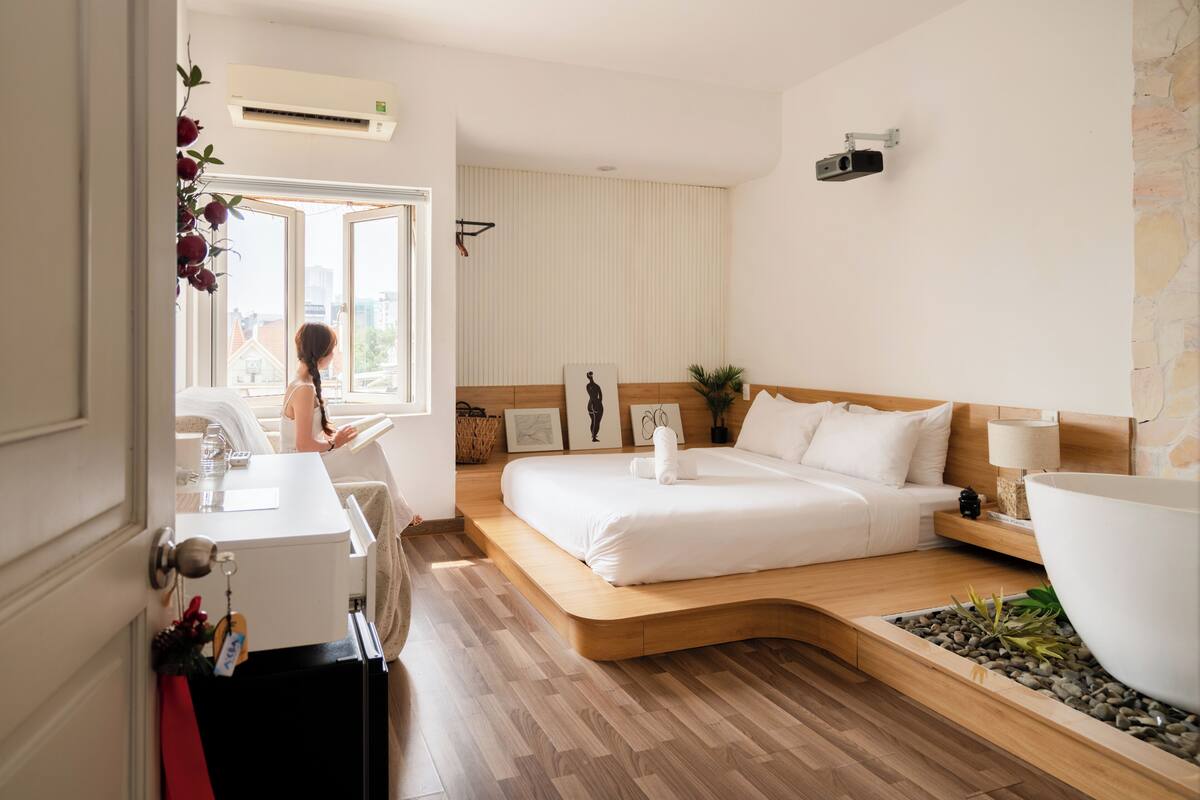 Ein modernes Hotelzimmer mit Bett, Nachttisch, Lampe und Blick auf die Stadt.