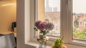 A room with a window, a table with a book, a vase with flowers, and a fruit bowl. - Cham's Hotel & Homestay (Ho Chi Minh City)