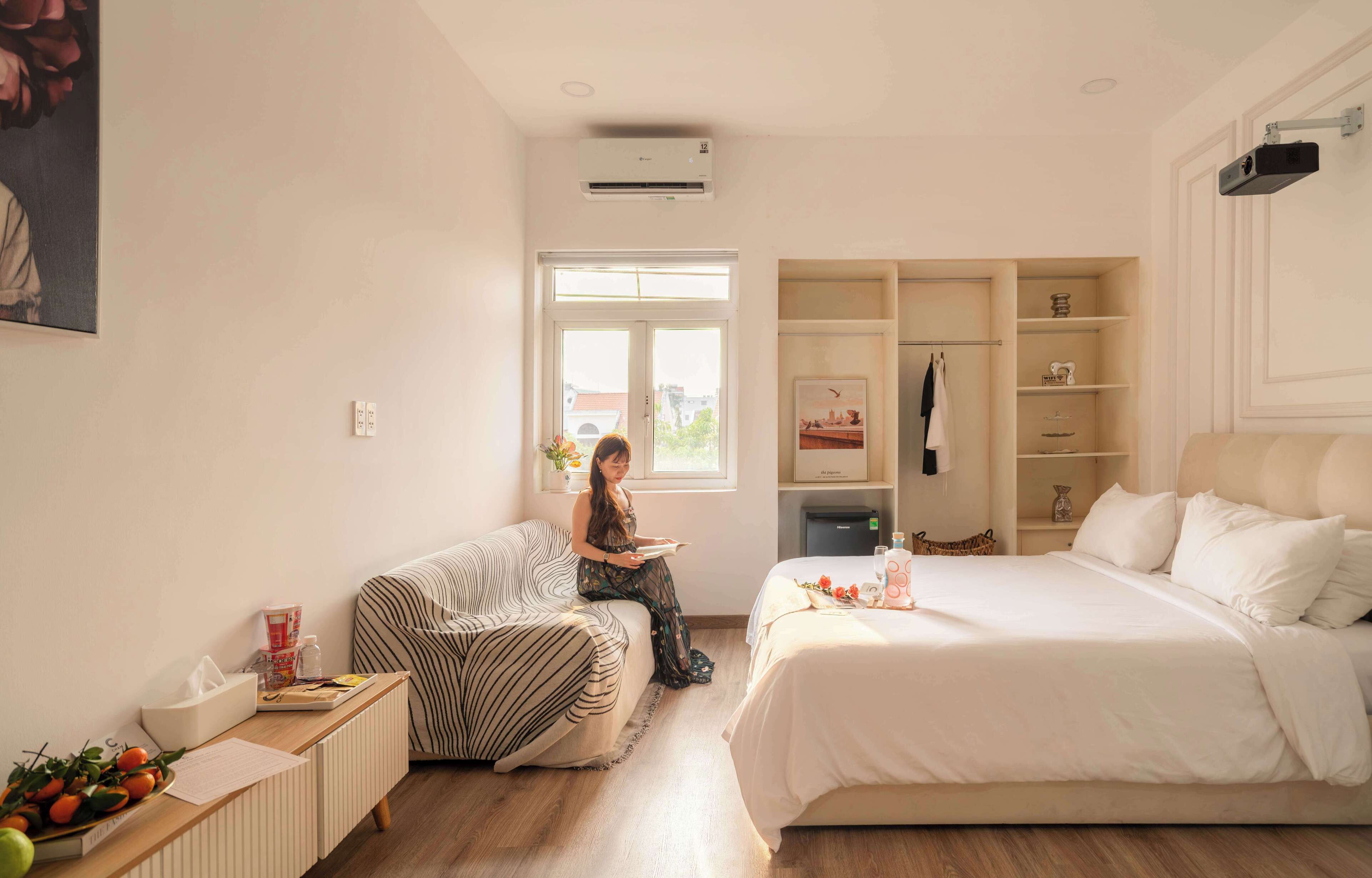 A modern bedroom with a bed, a sofa, a radiator, a window, and a wardrobe.
