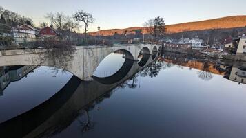 A bridge over a calm body of water with a clear reflection, surrounded by buildings and hills.