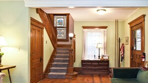 A staircase with wooden railings and a stained glass window at the top. - Balcony Room in Victorian Home private bath (Shelburne Falls)