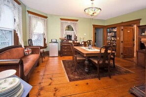 Un coin repas accueillant avec une table et des chaises en bois, un réfrigérateur et une bibliothèque.