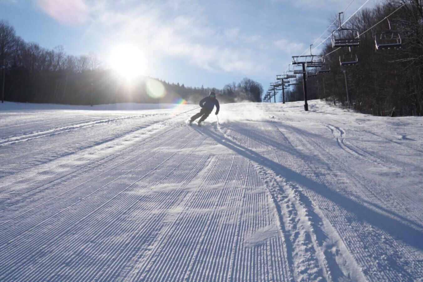 Une piste de ski enneigée, avec des remontées mécaniques et des arbres en arrière-plan.