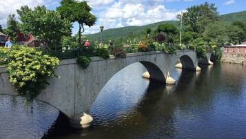 A stone bridge over a calm river with greenery on either side.