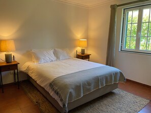 A bedroom with a bed, two bedside lamps, a window with curtains, and a rug. - Cottage 'Casa Dos Pinheiros' with Private Pool, Wi-Fi and Air Conditioning (Vila Nova de Santo André)