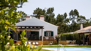 Une maison avec une piscine, du mobilier d’extérieur et une pergola.