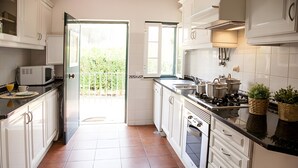 Une cuisine avec des meubles blancs, un four à micro-ondes, une cuisinière et un évier.