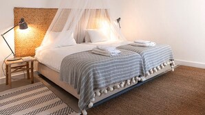 Una cama con dosel, lámparas de noche y una alfombra estampada.