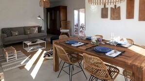 Un comedor con una mesa de madera preparada para cuatro personas, rodeada de sillas de mimbre.