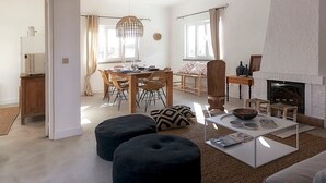 Un salón amplio con chimenea, un comedor con mesa y sillas de madera, y una mesa de centro moderna.